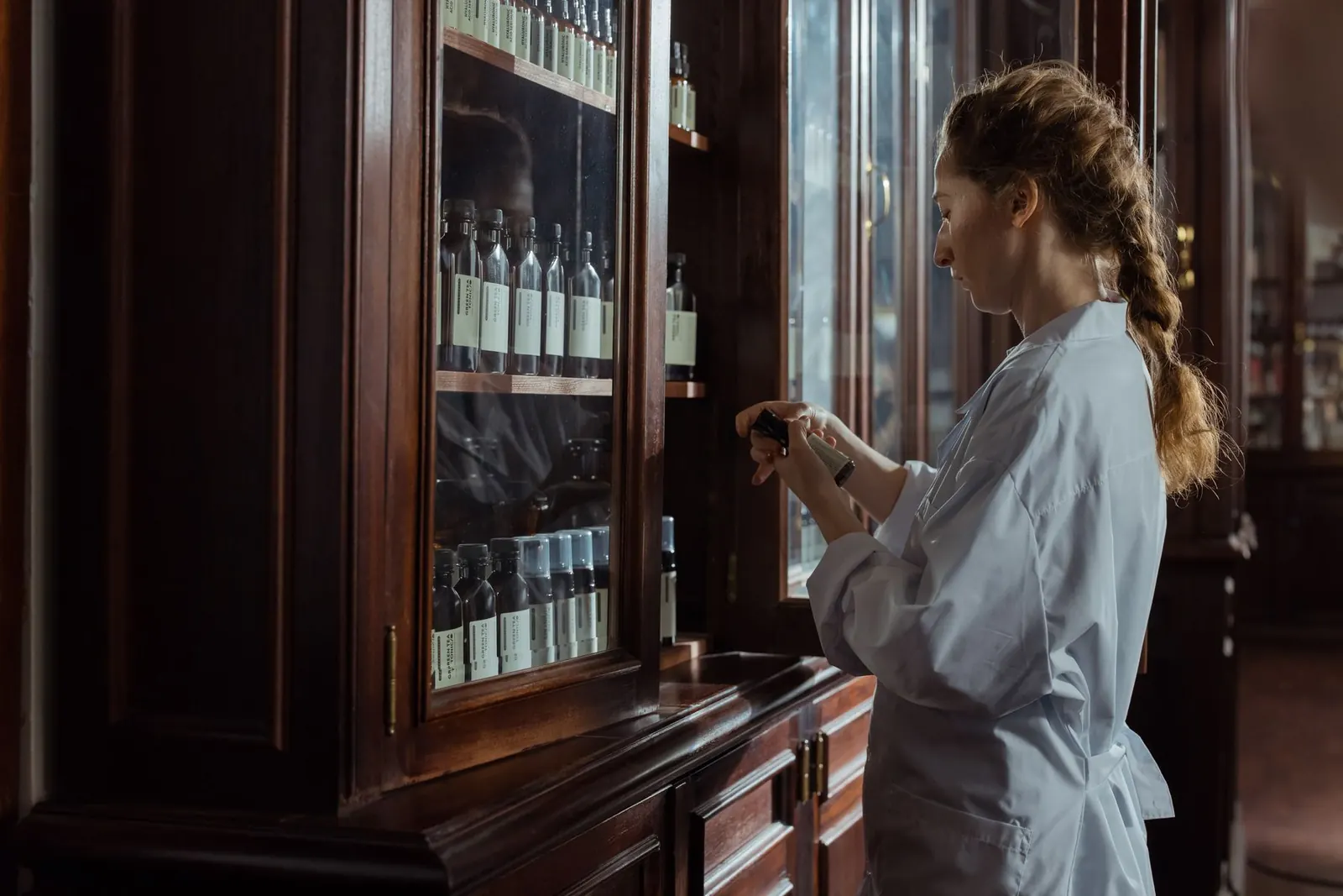 A pharmacist selecting preparations from an apothecary cabinet